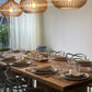Dining room with a long wooden table set for dinner, featuring modern chairs and decorative pendant lights.